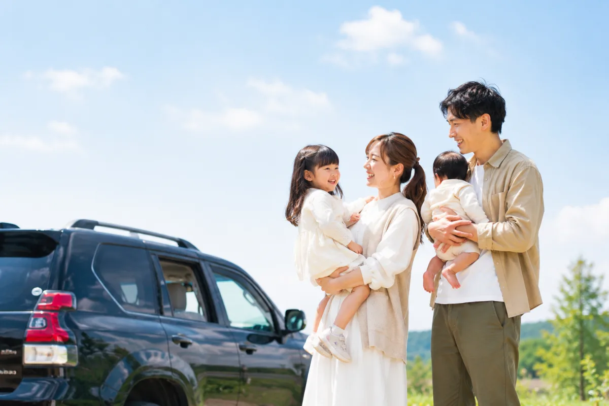 車のそばで笑顔の家族